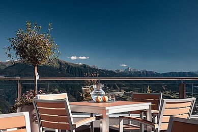 Blick auf einen gedeckten Tisch auf der Terrasse mit dem Südtiroler Bergpanorama im Hintergrund