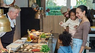 Eine Familien mit zwei Kindern steht am Buffet und betrachtet die Speisenauswahl.