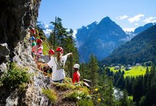 Kinder klettern an einer Steinwand hoch.