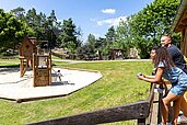 Eltern blicken auf den Spielplatz auf dem Außengelände des Family Club Harz.