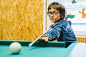 Kleiner Junge spielt Billard im Happy-Club des Familienhotels Ottonenhof im Sauerland.