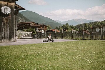 Junge fährt über das Hotelgelände vom Hotel Tirolerhof mit dem Go-Kart