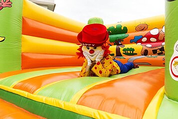 Das Familotel-Maskottchen "Happy" liegt in einer großen Hüpfburg des Familienhotels Egger.