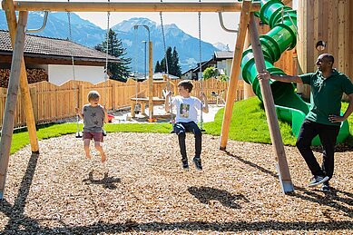 Kinder spielen auf dem Outdoor-Spielplatz mit Röhrenrutsche im Familienhotel Tirolerhof.