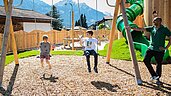 Kinder spielen auf dem Outdoor-Spielplatz mit Röhrenrutsche im Familienhotel Tirolerhof.