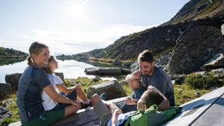 Familie genießt die Aussicht auf den See und auf die Berge im Familienurlaub in Südtirol.