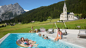 Kinder schwimmen im Sommer im Pool vom Familienhotel Bella Vista in Südtirol.