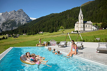 Kinder schwimmen im Sommer im Pool vom Familienhotel Bella Vista in Südtirol.