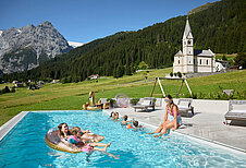 Kinder schwimmen im Sommer im Pool vom Familienhotel Bella Vista in Südtirol.