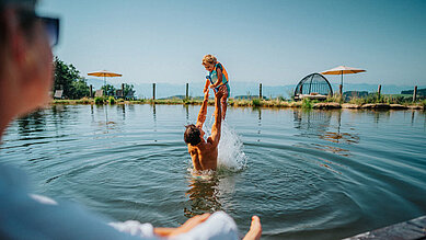 Vater und Sohn planschen im Natur-Badesee im Familien Resort Petschnighof