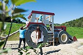 Familie spielt zusammen auf einem outdoor Traktor-Spielplatz im Familienhotel Schreinerhof.