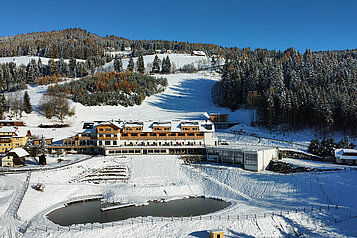 Winterliche Luftaufnahme des Familienhotels Petschnighof in Kärnten.