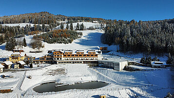 Winterliche Luftaufnahme des Familienhotels Petschnighof in Kärnten.