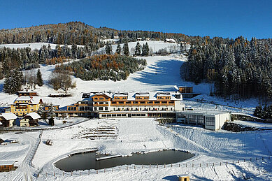 Winterliche Luftaufnahme des Familienhotels Petschnighof in Kärnten.