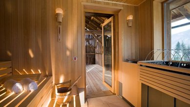 Im Familienhotel Ramsi in Kärnten lädt eine gemütliche Sauna mit Holzverkleidung und Blick ins Freie zum Entspannen und Wohlfühlen ein