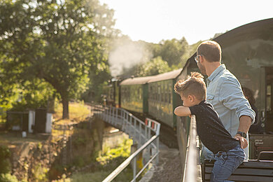 Vater und Sohn sehen sich die historische Bahn im Erzgebirge an.