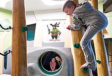 Junge klettert in der Räuberhöhle des Familienhotels Amiamo im Salzburger Land.