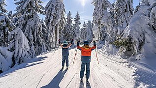 Zwei Kinder beim Skifahren im Familienurlaub in Deutschland im Winter.