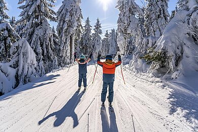 Zwei Kinder beim Skifahren im Familienurlaub in Deutschland im Winter