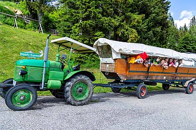 Familien auf einer Traktorfahrt durch die Landschaft im Urlaub im Hotel Alpengasthof Hochegger in Kärnten