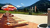 Großer Volleyballplatz mit Liegen und Sonnenschirmen auf dem Gelände vom Familienhotel Sonngastein in Bad Gastein.