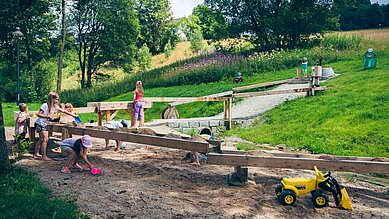 Wasserspielplatz mit großem Sandkasten und Spielzeugbaggern im Familienhotel Mein Krug im Fichtelgebirge.