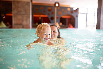 Mutter und Sohn schwimmen entspannt im Hallenbad des Familienhotels Landhaus zur Ohe