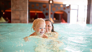 Mutter und Sohn schwimmen entspannt im Hallenbad des Familienhotels Landhaus zur Ohe