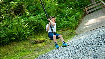 Glücklicher Junge auf dem Waldspielplatz des Spa- & Familien-Resorts Krone im Allgäu.