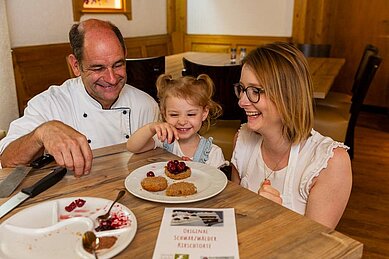 Gastgeber des Familienhotels Engel sitzt bei seinen Gästen am Tisch.