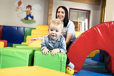 Ein Baby spielt unter Aufsicht im Happy Club im Familienhotel