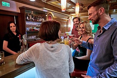 Gemeinsam mit Freunden an der Bar etwas trinken im Familienhotel Amiamo im Salzburger Land.