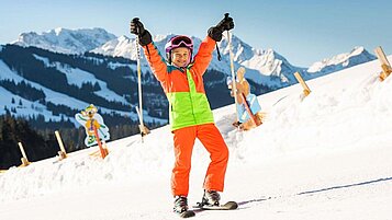 Kind steht auf der Skipiste im familienfreundlichen Skigebiet im Familienurlaub in Bayern.