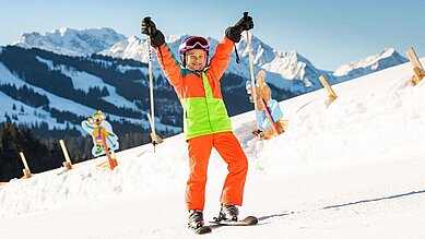 Kind steht auf der Skipiste im familienfreundlichen Skigebiet im Familienurlaub in Bayern.