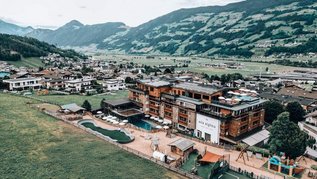 Das Familienhotel Mia Alpina in Tirol von oben mit Poolbereich, Liegewiese und Bergpanorama.