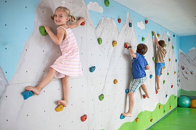 Drei Kinder klettern an der Kletterwand des Familienhotels Kaiserhof an der Zugspitze.