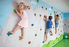 Drei Kinder klettern an der Kletterwand des Familienhotels Kaiserhof an der Zugspitze.