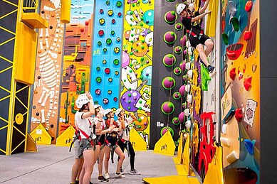 Teens stehen vor einer großen Boulderwand im Familienhotel Kolping Hotel Spa & Family Resort in Ungarn.