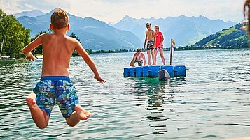 Kinder spielen im Wasser auf einer Badeinsel im Familienhotel Amiamo im Salzburger Land.