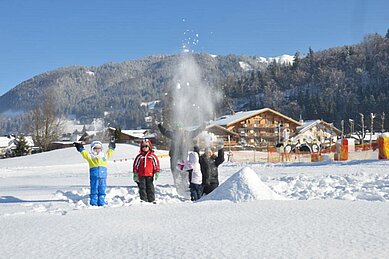 Drei kleine Mädchen stehen auf Skiern in Skiausrüstung am Übungslift des Familienhotels Landgut Furtherwirt in Tirol.