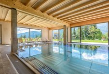 Lichtdurchfluteter Indoorpool mit traumhaftem Bergblick im Familienhotel Ramsi in Kärnten