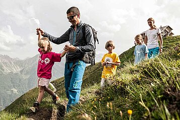 Familie mit Baby wandert durch die schöne Landschaft im Familienurlaub in Tirol.