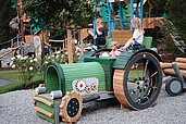 Ein paar Kinder spielen auf dem Spiel-Traktor auf dem Spielplatz am Familienhotel Habachklause