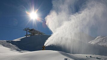 Eine Schneekanone beschneit die Skipisten im Winter auf den Pisten rund um das Familienhotel Zauchenseehof im Salzburger Land