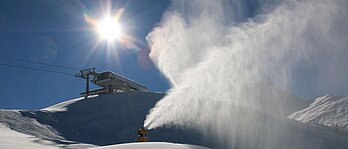 Eine Schneekanone beschneit die Skipisten im Winter auf den Pisten rund um das Familienhotel Zauchenseehof im Salzburger Land