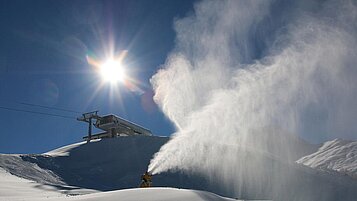 Eine Schneekanone beschneit die Skipisten im Winter auf den Pisten rund um das Familienhotel Zauchenseehof im Salzburger Land