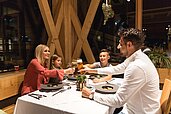 Eine Familie sitzt im Restaurant mit Getränken im Familienhotel Almfamilyhotel Scherer in Tirol.