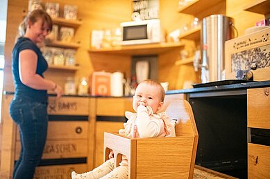 Mutter und Kind sind in der Babyecke und bedienen sich am Babybuffet des Familienhotels Landhau szur Ohe im Bayerischen Wald.