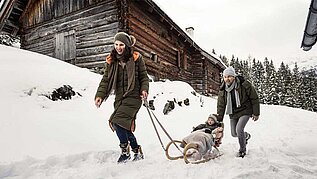 Eine Mutter zieht ihr Kind auf einem Schlitten durch den Schnee