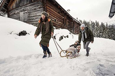 Eine Mutter zieht ihr Kind auf einem Schlitten durch den Schnee